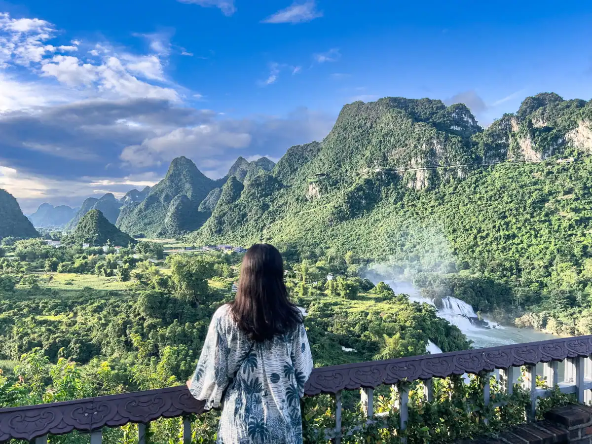Woman overlooking Ban Gioc Waterfall and mountains in Vietnam.