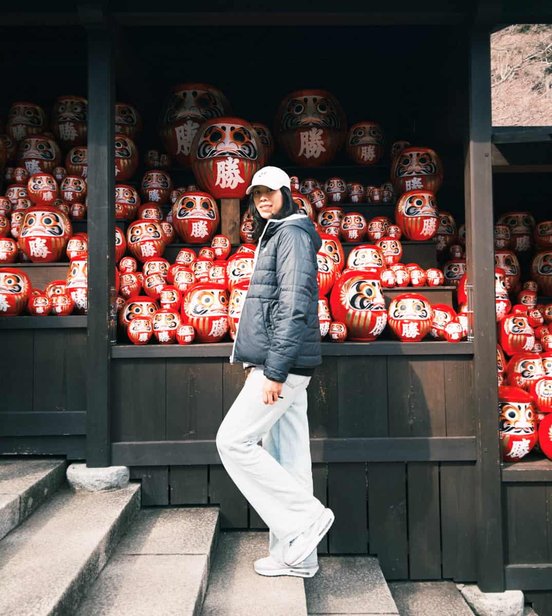 Woman stand in front of the Daruma in Katsuō-ji Temple in Osaka.